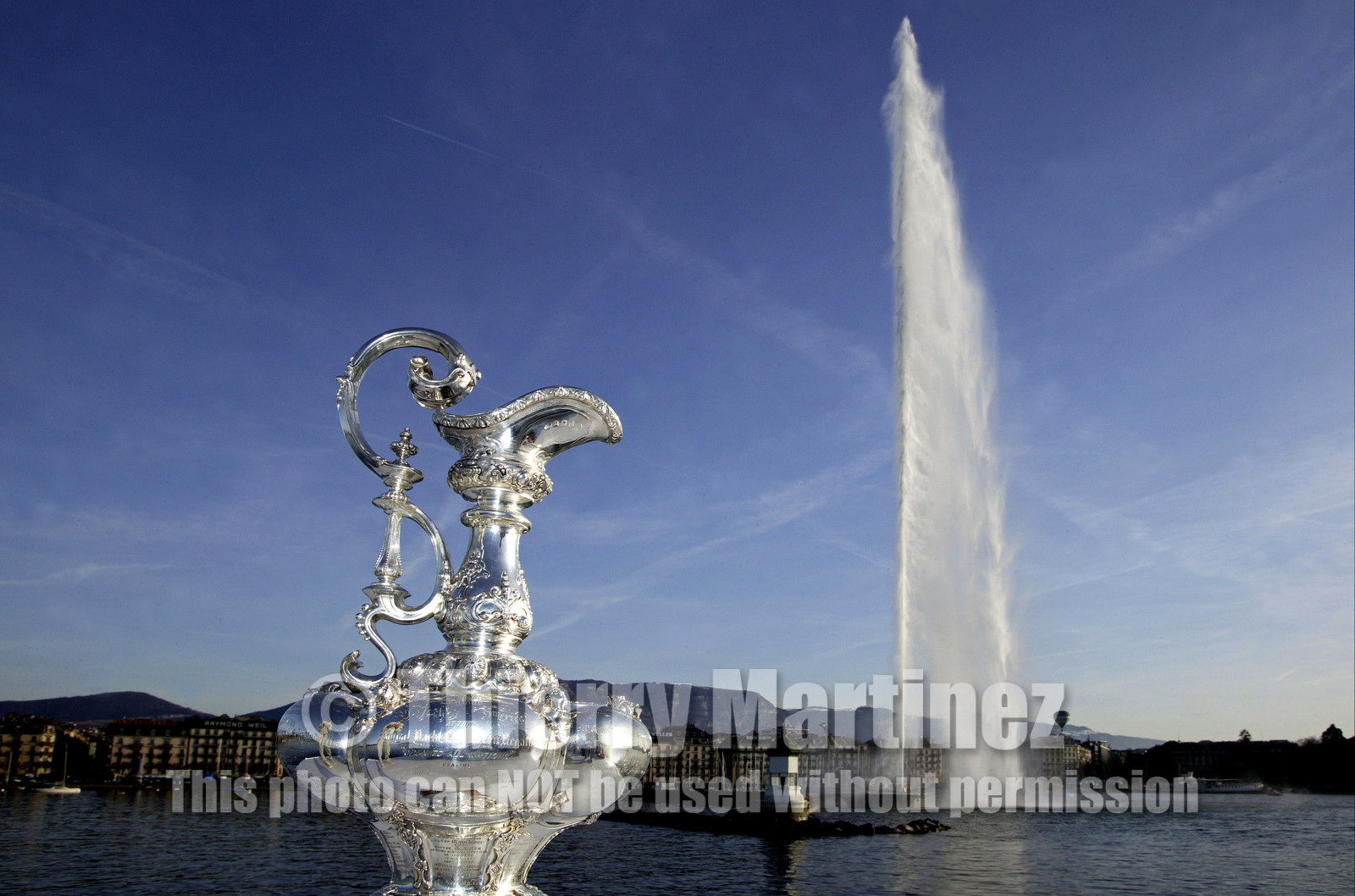 03_2294D ©Th.Martinez. Geneva , Switzerland. America's Cup 2003. 9th March 2003.Alinghi Team winner of America's Cup 2003..The America's Cup on the way to her new home, La Societe Nautique de Geneve (which is Alinghi Yacht Club). Alinghi Team and the CUP did a short trip by the Lac to arrive at La Nautique. On the way stop for a photo The Cup with jet deaude Geneve in the backgroung.