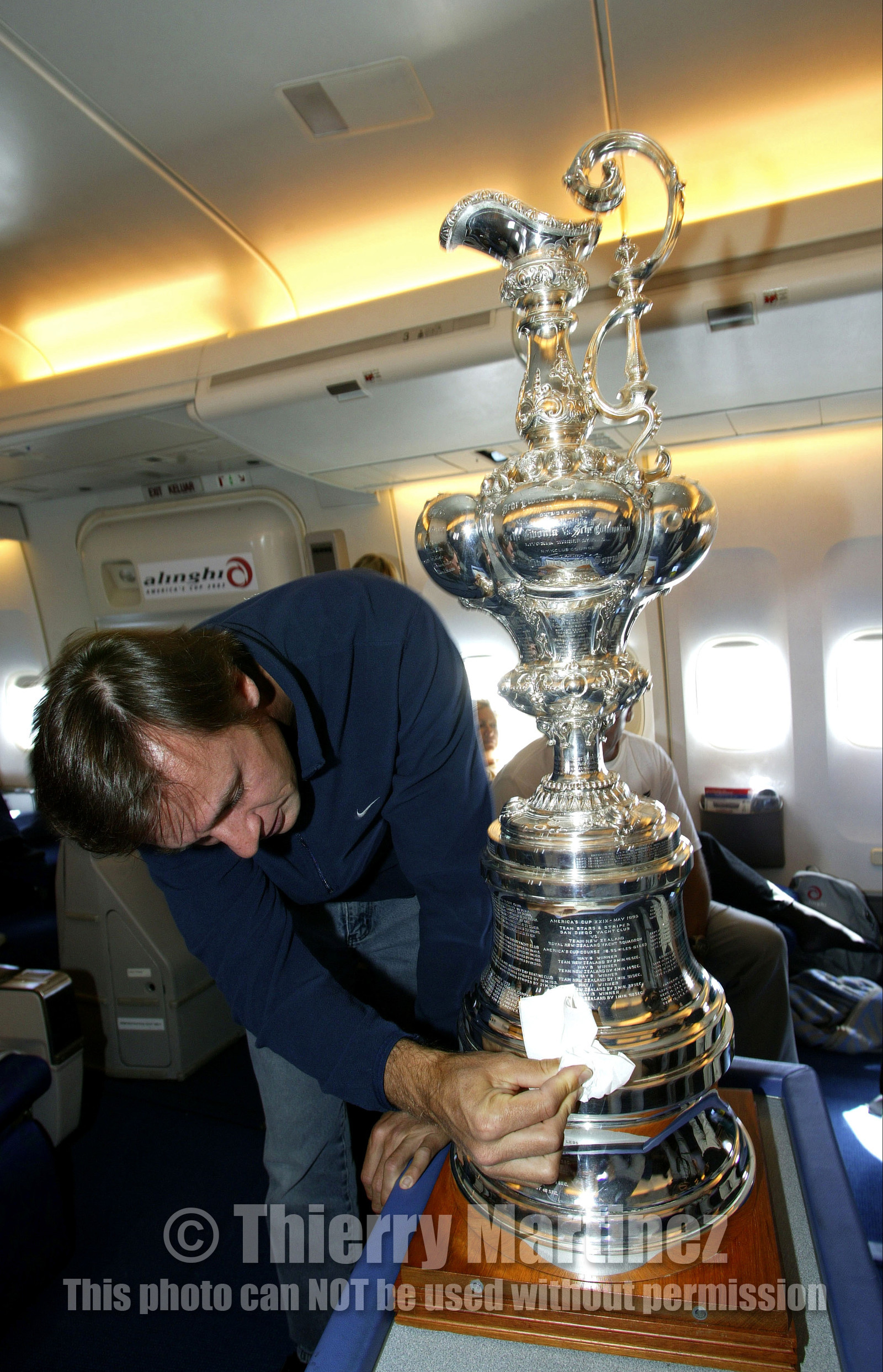 03_2203D ©Th.Martinez - Airplane (Auckland to Geneva) . America's Cup 2003. 8th March 2003.Alinghi Team winner of America's Cup 2003..Alinghi's president and navigator Ernesto Bertarelli, cleaning THE CUP  in the plane to Geneva....
